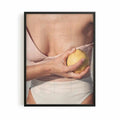 Editorial Mediterranean photography framed print showing a fresh lemon held against sun-kissed skin with soft neutral tones and warm citrus colours.