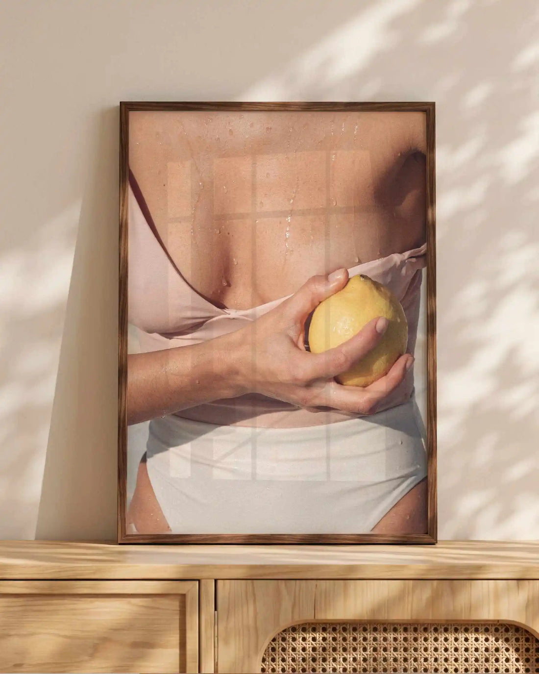 Editorial Mediterranean photography framed print showing a fresh lemon held against sun-kissed skin with soft neutral tones and warm citrus colours.