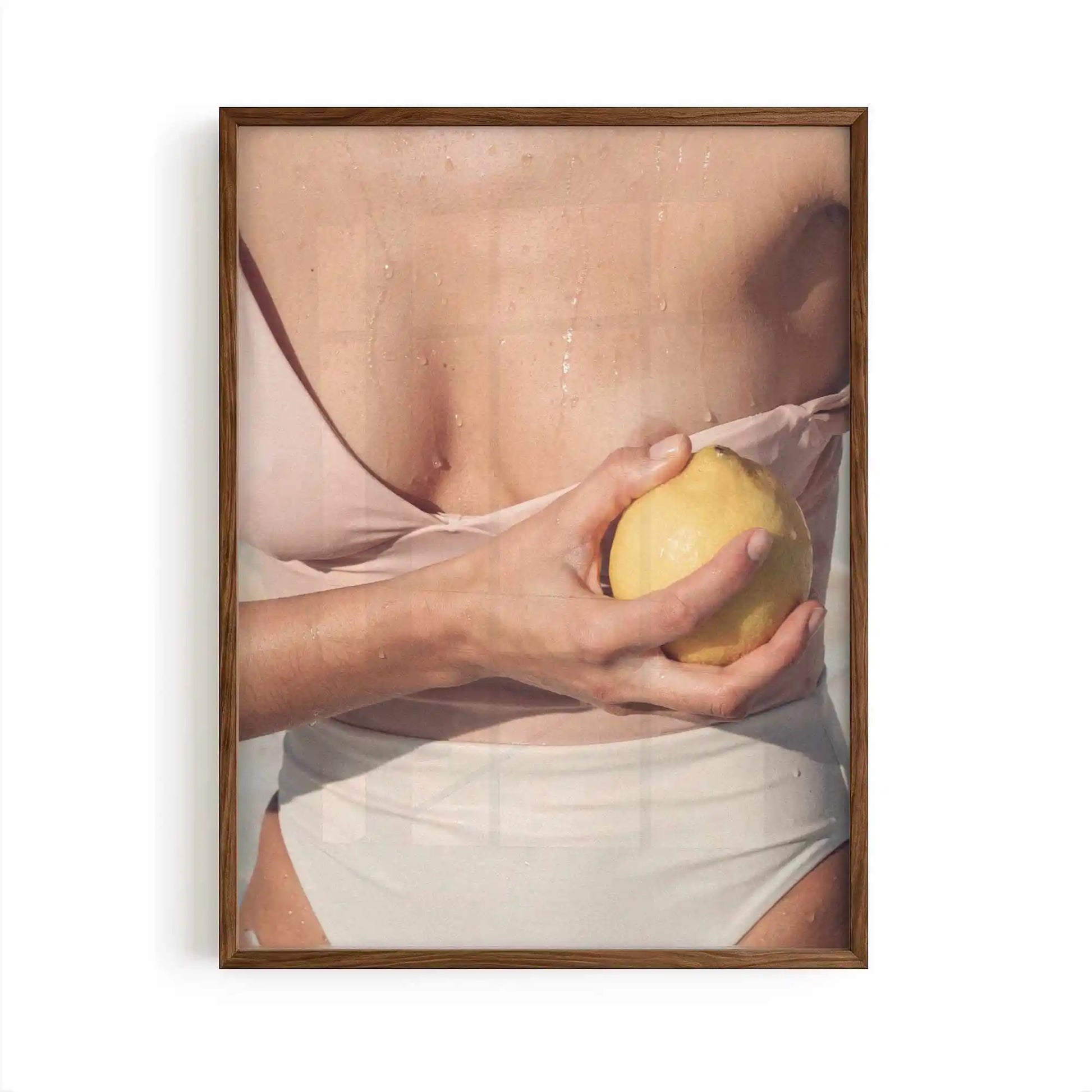 Editorial Mediterranean photography framed print showing a fresh lemon held against sun-kissed skin with soft neutral tones and warm citrus colours.