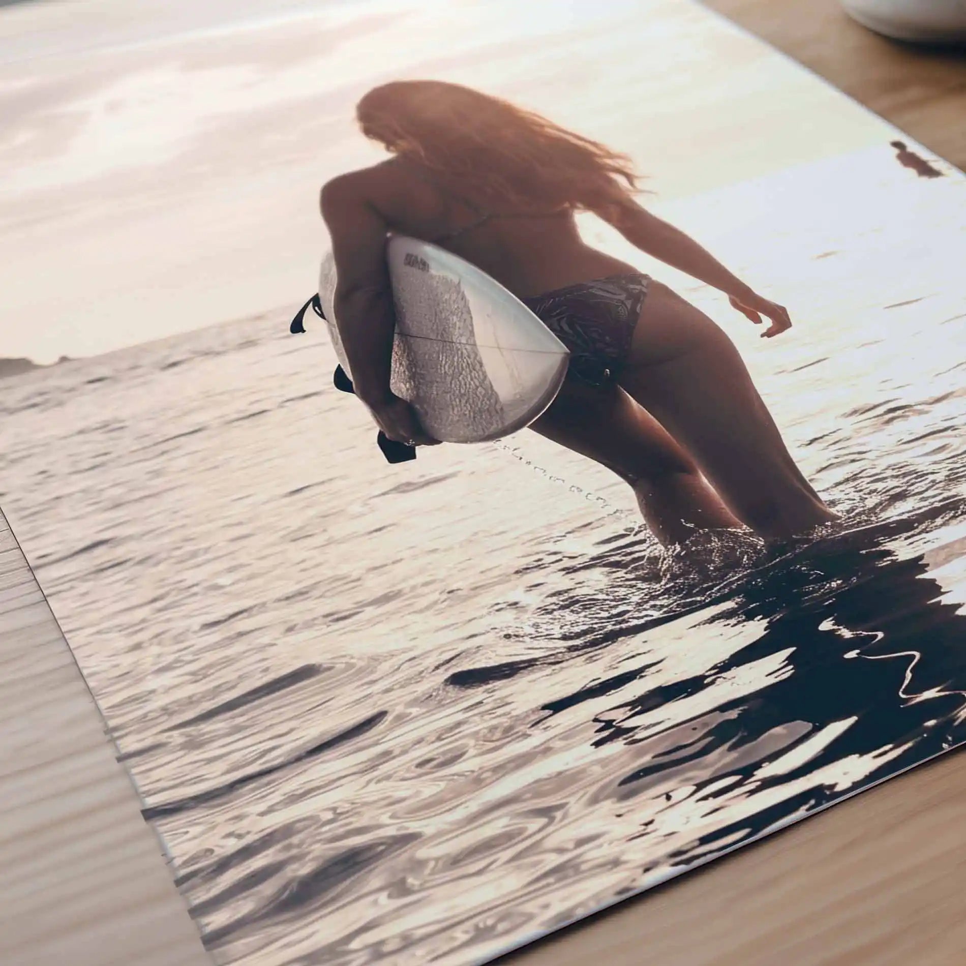 Surfer girl walking into the ocean at golden hour carrying a surfboard during sunset, creating a peaceful coastal photography  poster detail