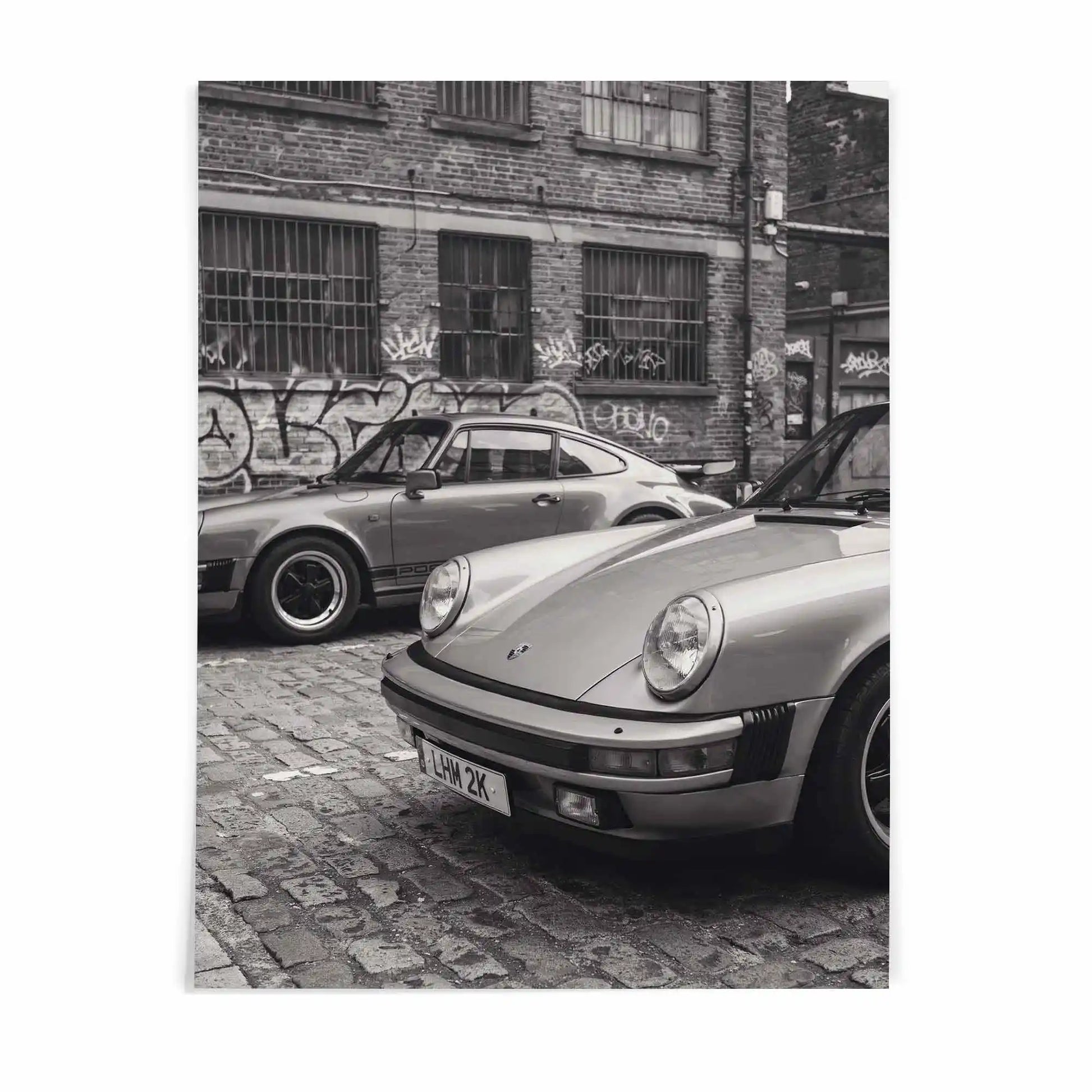 Nine Eleven Porsche 911 black and white wall art by After Hours Gallery featuring two classic sports cars in an industrial urban setting.
